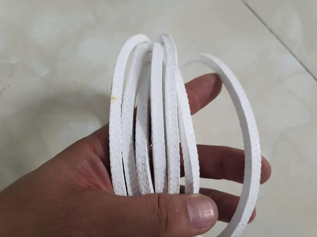 Cách lắp dây tết chèn: các vòng dây PTFE trắng đã cắt sẵn xòe trên lòng bàn tay