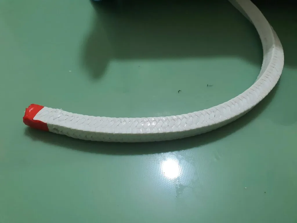 Cách lắp dây tết chèn: đầu dây PTFE trắng quấn băng đỏ để giữ sợi không tưa