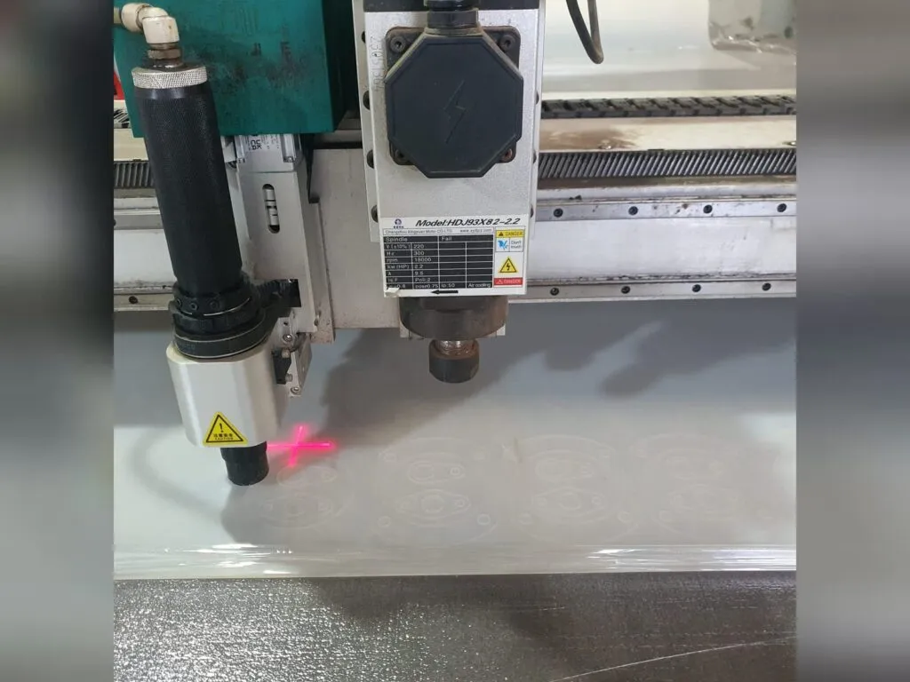 Cắt gioăng mặt bích bằng máy CNC: đầu dao và tia định vị đỏ trên tấm vật liệu