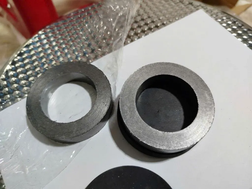 Graphite chịu nhiệt bao nhiêu độ: hai vòng graphite ép xám đặt cạnh nhau trên giấy trắng