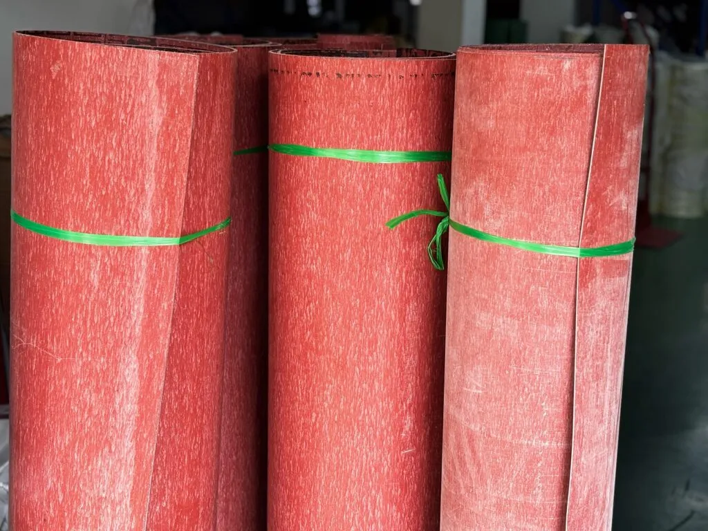 Tấm amiang chịu nhiệt màu đỏ cuộn thành ba ống, buộc dây xanh đứng cạnh nhau