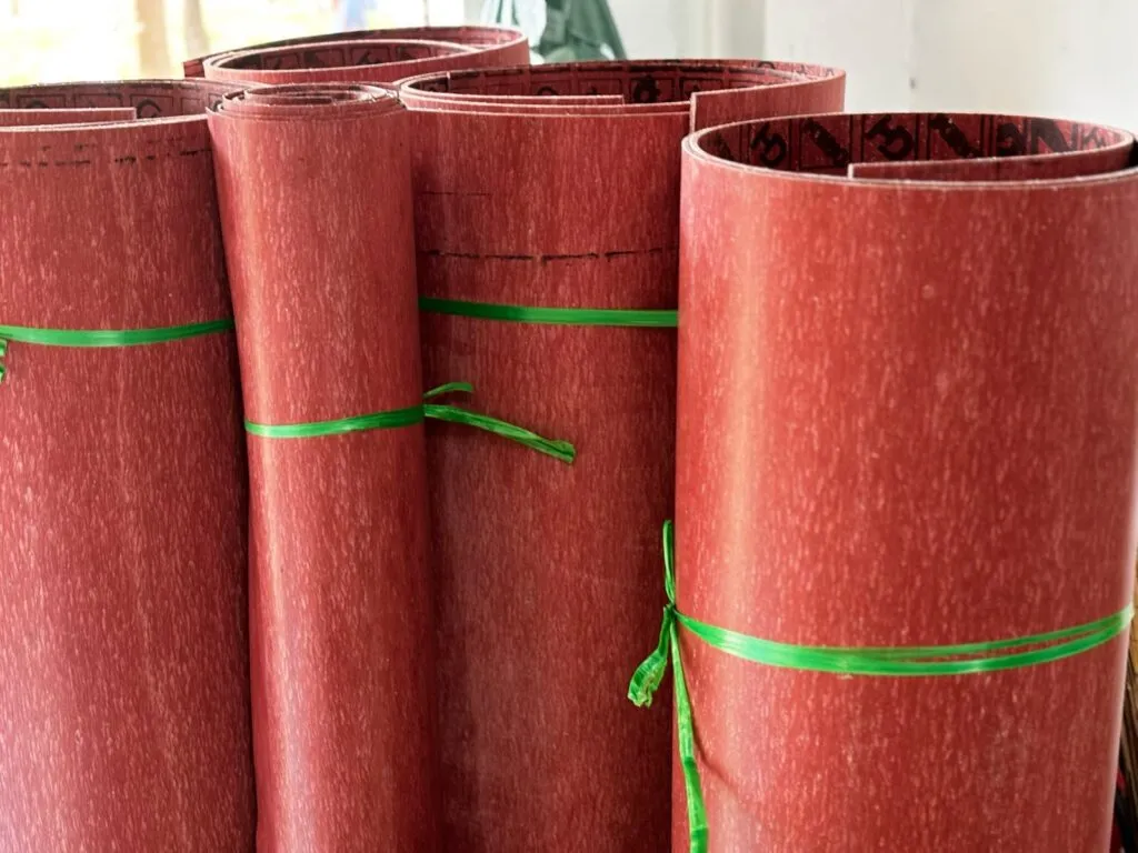 Tấm amiang đỏ nguyên khổ cuộn thành ống, buộc dây xanh xếp đứng trong kho
